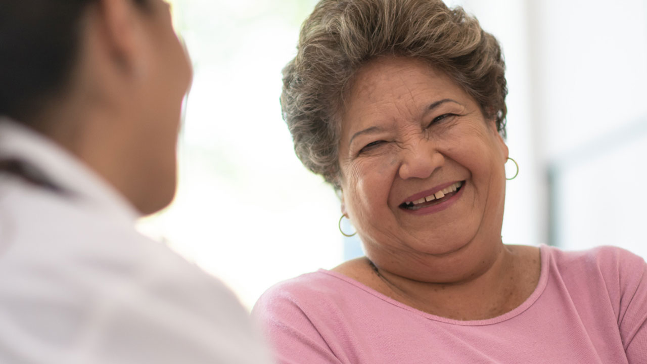 Senior woman smiling while in conversation with doctor